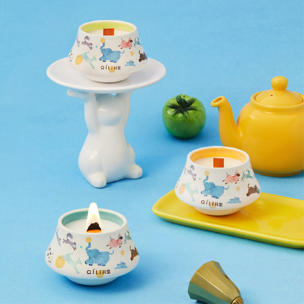 Illustrated ceramic cup scented candle with flame on a small saucer