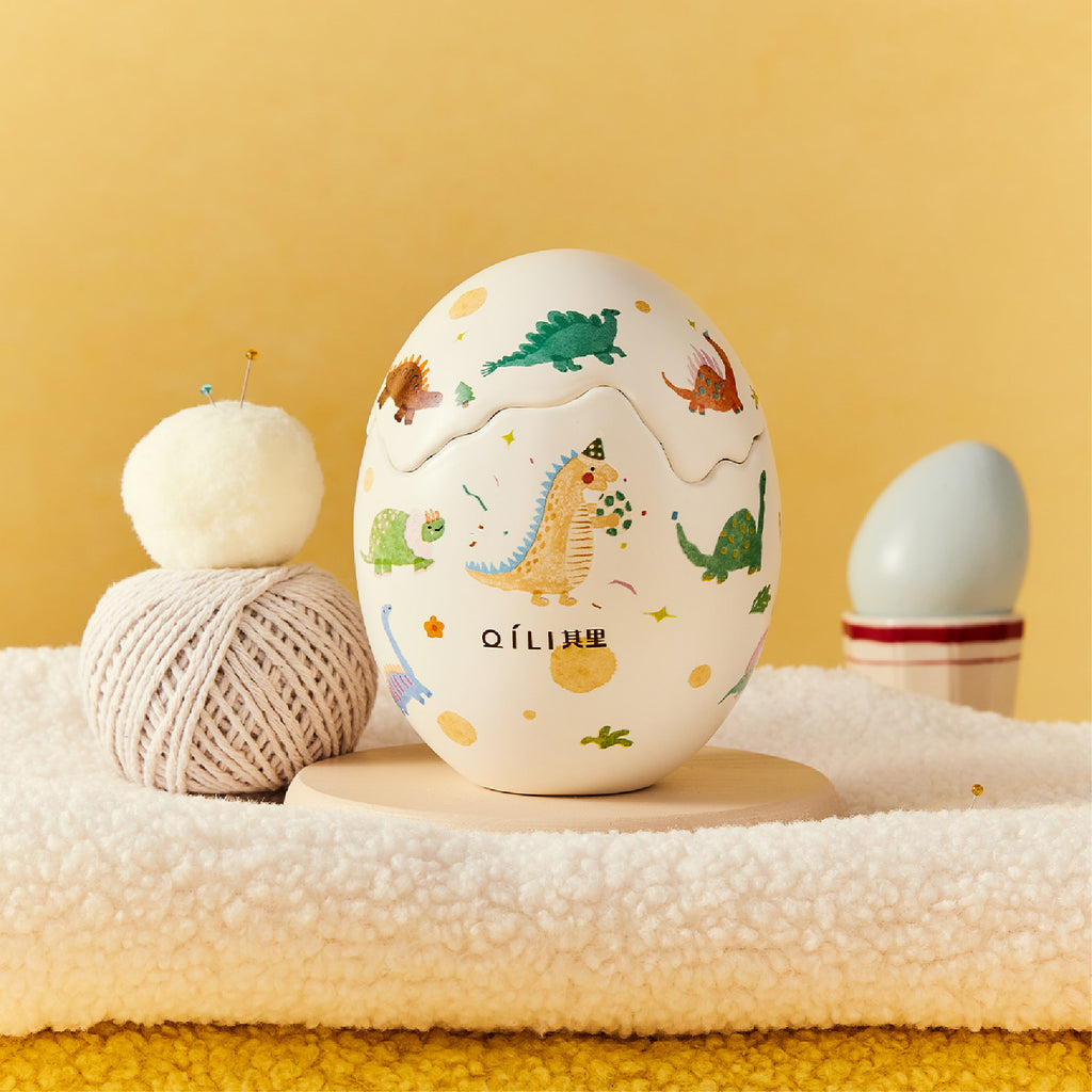 Dinosaur egg scented candle with pastel dino print on white egg-shaped container