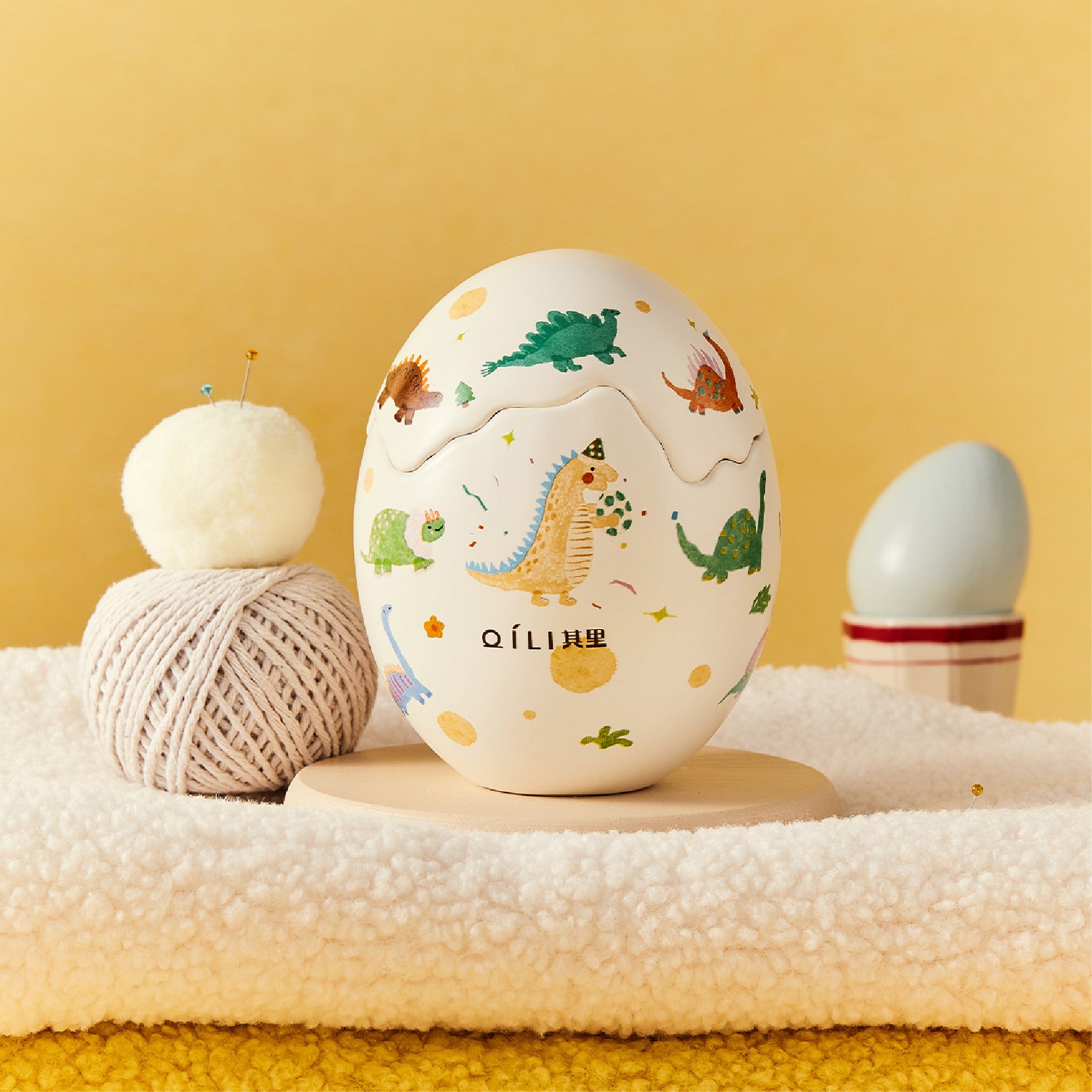 Dinosaur egg scented candle with pastel dino print on white egg-shaped container