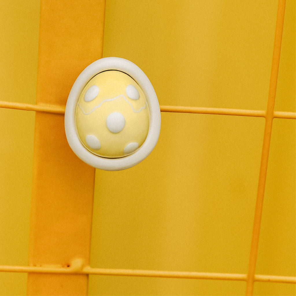 Yellow egg-shaped car diffuser scent pod on yellow panel